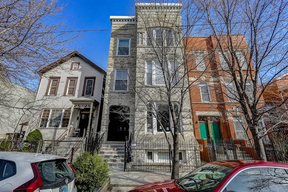 Front view of a three-story residential building with brick and stone facade.