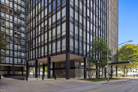 Front view of a modern high-rise building with glass windows and steel structure.