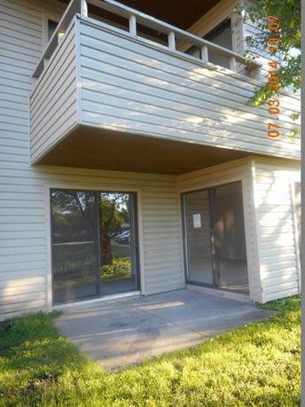 Front view of a building with a balcony and sliding glass doors.