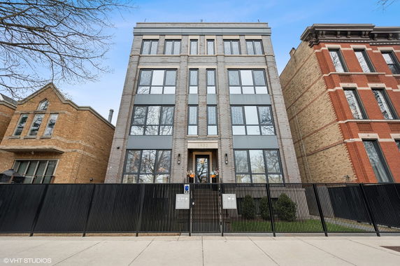 Front view of a multi-story building with large windows and a fenced entrance.