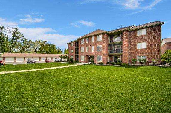 Front view of a three-story brick apartment building with balconies.