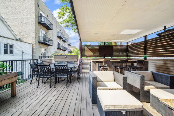 Rooftop area with seating and bar setup, featuring outdoor furniture and railing.