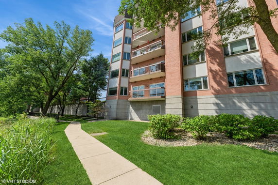 Front view of a multi-story brick building with balconies and large windows.