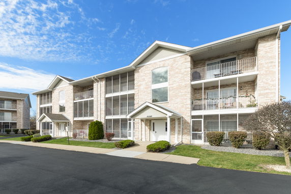 Front view of a multi-story apartment building with balconies and a central entrance.