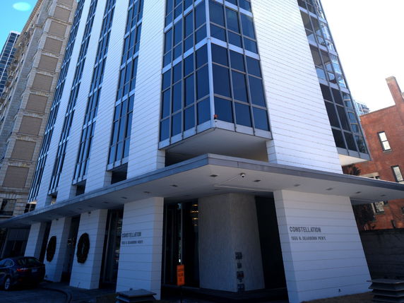 View of a modern multi-story building with large glass windows and a cantilevered entryway.