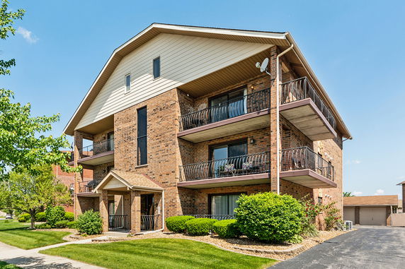 Front view of a multi-story brick apartment building with balconies.