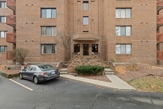 Front view of a multi-story brick building with an entrance and parking area.