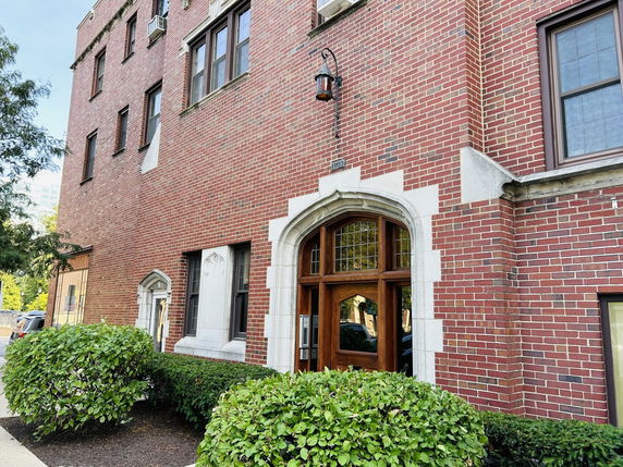 Front view of a red brick multi-story building with wooden entrance door.