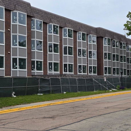 Front view of a multi-story building with numerous windows under construction.