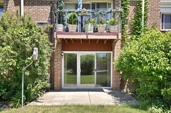 Front view of a brick building with balcony and glass doors.