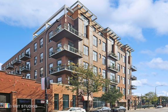Front view of a multi-story brick apartment building with balconies.
