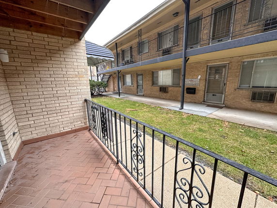 View of a brick apartment building with a small balcony.