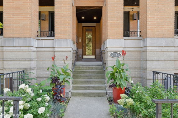 Front view of a house entrance with stairs and potted plants.