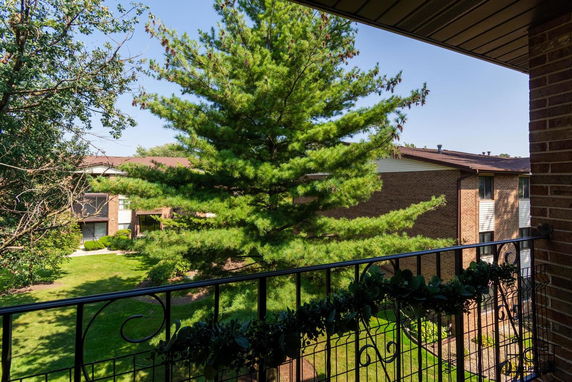 View from a balcony overlooking a tree and a brick building.