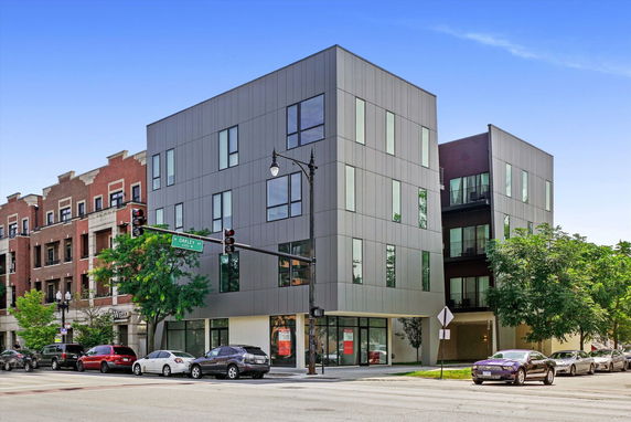 Front view of a modern multi-story building with large windows and a minimalist design.