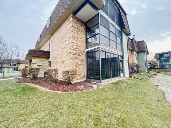 View of a multi-story brick building with large glass windows and a sloped roof.
