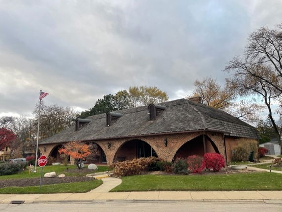 Front view of a single-story brick building with arched entrances and a shingled roof.
