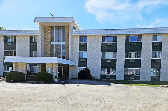 Front view of a three-story building with multiple windows and a covered entrance.