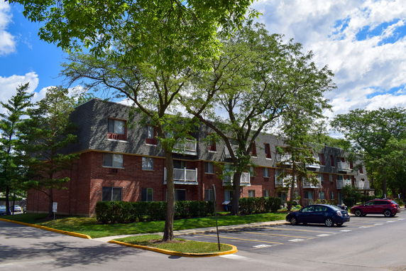Front view of a multi-story brick apartment building with balconies.