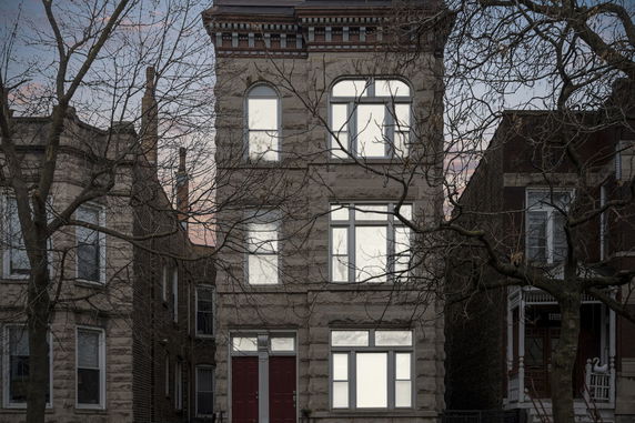 Front view of a three-story townhouse with multiple windows and a red front door.