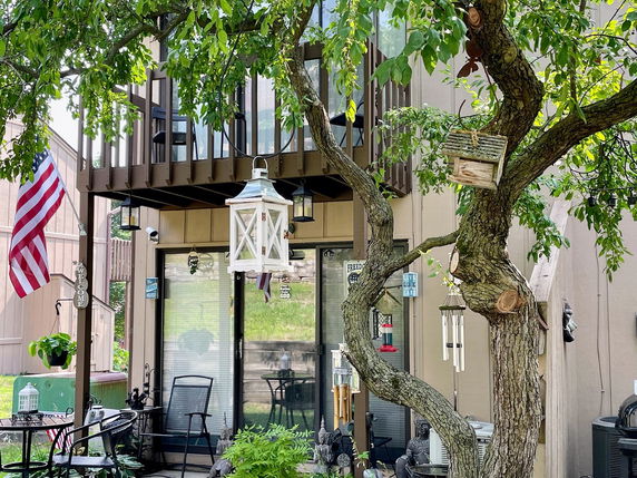 Front view of a house with a balcony and patio seating area.