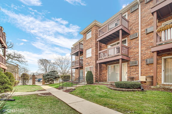 Front view of a multi-story brick residential building with balconies.
