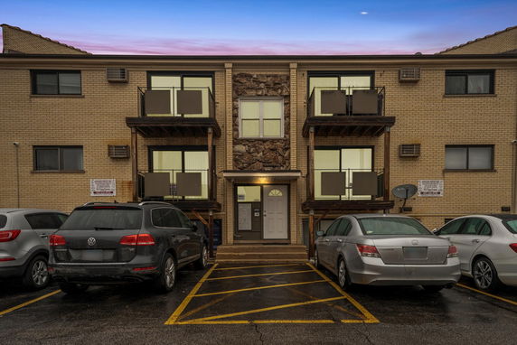 Front view of a two-story apartment building with balconies and parking area.