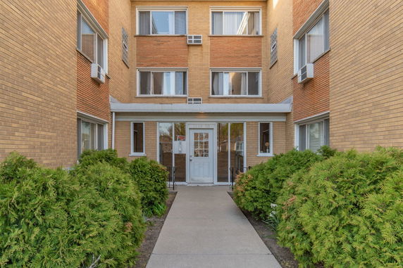 Front view of a multi-story brick building with glass entrance doors.