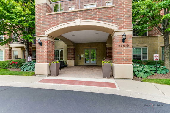 Front view of a multi-story brick building entrance with an archway and glass doors.