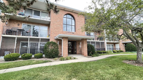 Front view of a three-story brick apartment building with balconies.
