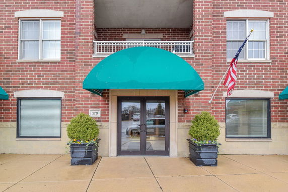 Front view of a brick building with green awnings and an entrance.