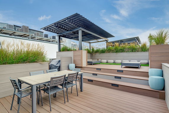 Rooftop area with patio furniture, a pergola, and decorative plants.