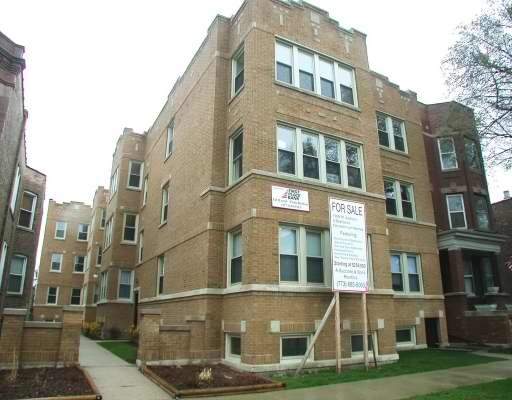 Front view of a brick multi-story apartment building with a for sale sign.