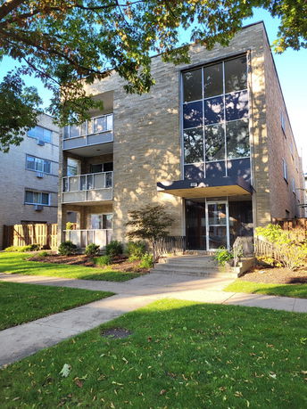 Front view of a multi-story apartment building with large windows and balconies.