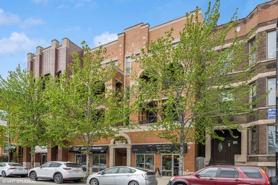 Front view of a multi-story brick building with storefronts on the ground level.
