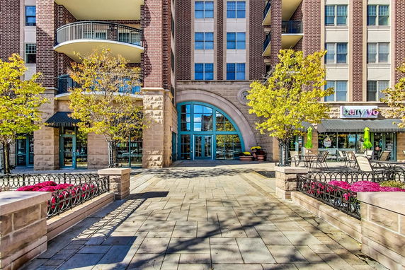 Front view of a multi-story building with balconies and a large arched entrance.