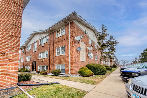 Front view of a multi-story brick apartment building with multiple satellite dishes.