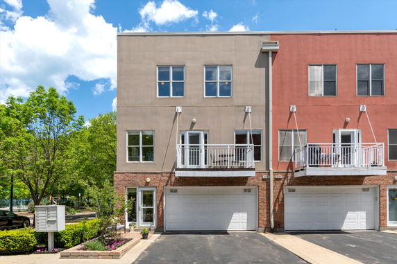 Front view of a two-story townhouse with a brick facade and double garage.