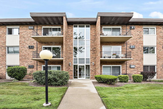 Front view of a three-story brick apartment building with balconies.