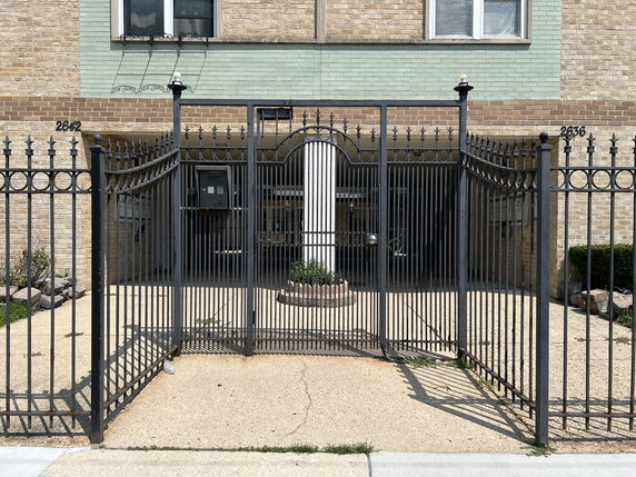 Front view of a building with wrought iron gate and keypad entry.