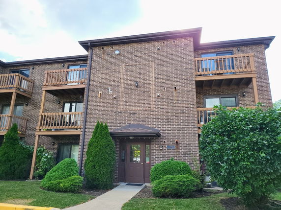 Front view of a multi-story brick apartment building with balconies.