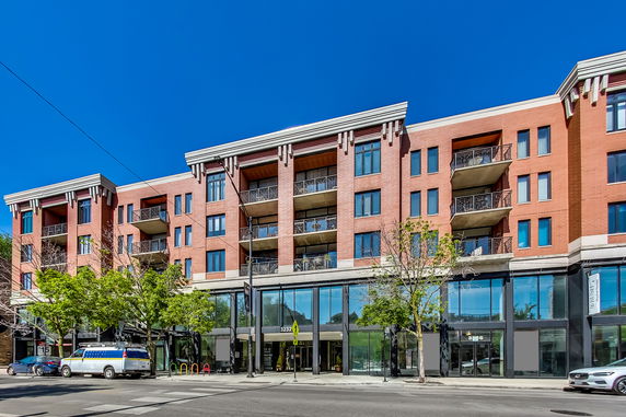 Front view of a multi-story red brick building with balconies and large glass entrances.