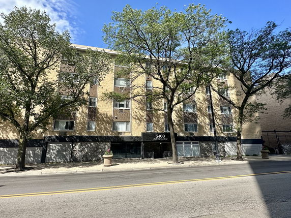 Front view of a multi-story brick building with large windows and an entrance canopy.