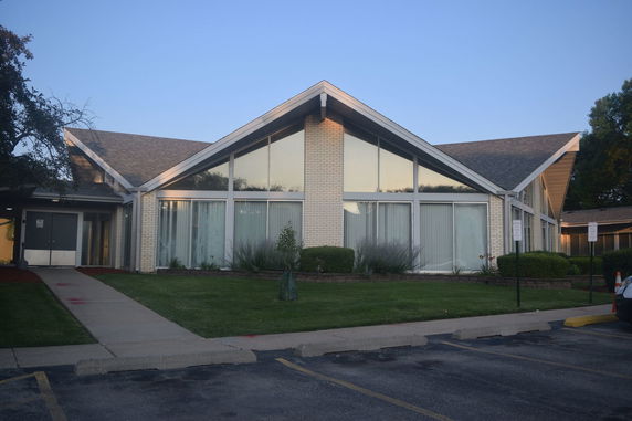 Front view of a modern building with large windows and a sloped roof.