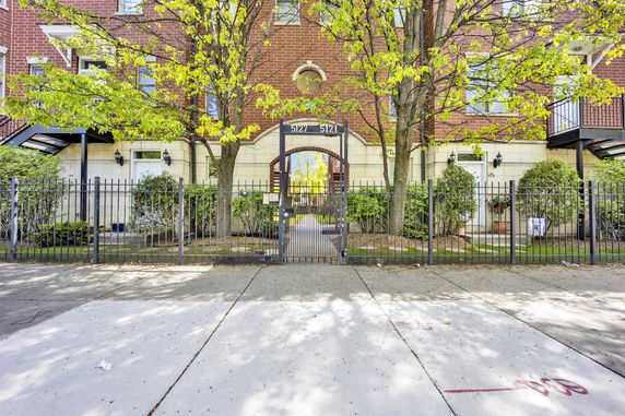 Front view of a brick residential building with a gated entrance.
