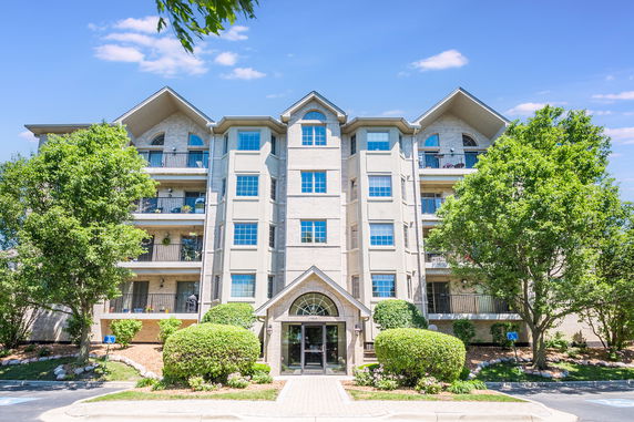 Front view of a multi-story residential building with balconies and a central entrance.