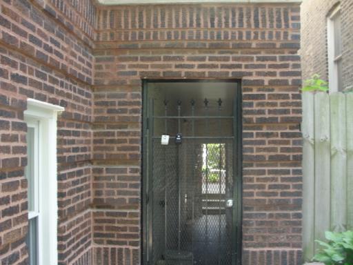 Front view of a brick building entrance with a metal gate.