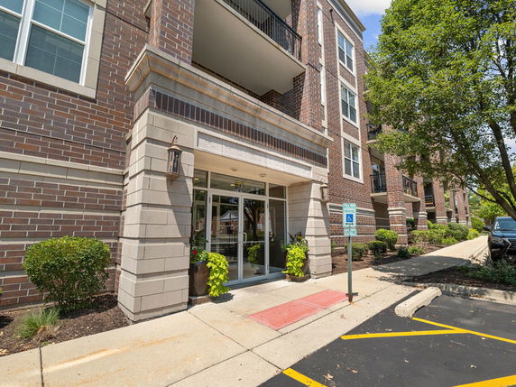 Front view of a multi-story brick building with balconies and large glass entrance.