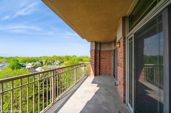 Balcony view overlooking a suburban neighborhood with houses and trees.