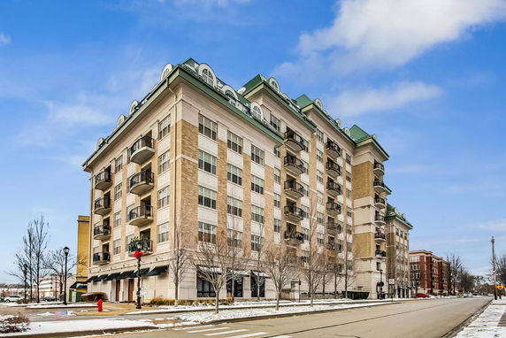 Front view of a multi-story apartment building with balconies and a green roof.